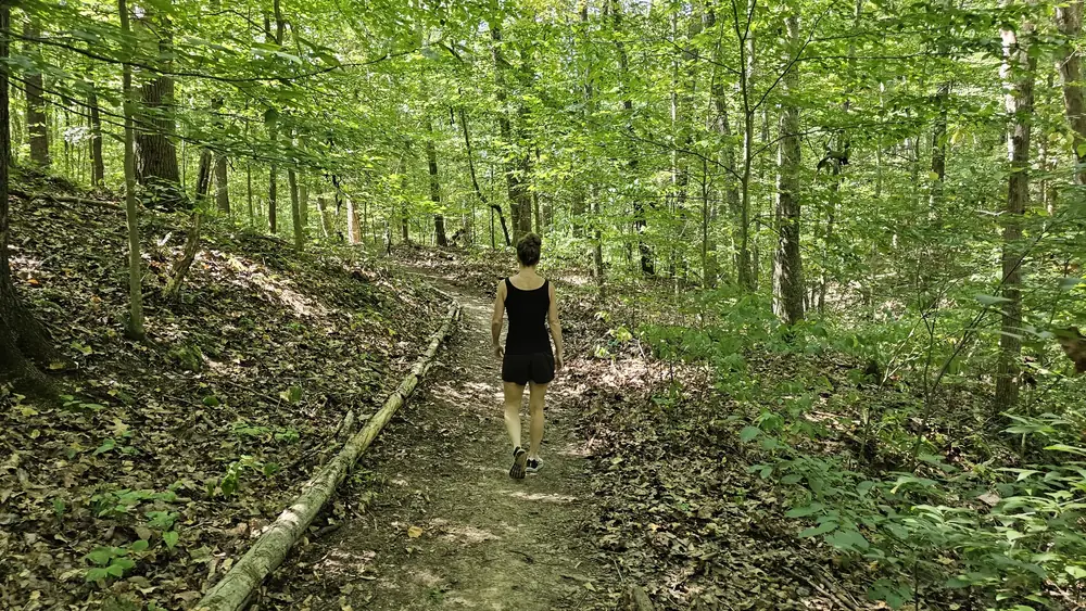 A solo guest walking the private wellness trail through the forest at Raven's Retreat Hocking Hills